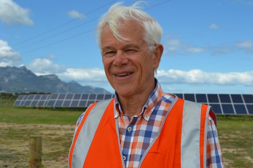 Michael Buck stands in front of solar panels