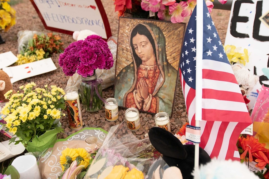 American flags, flowers, candles and a picture of the virgin Mary on the ground