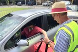 Man puts his ballot paper into a box that a voter official is holding near his car window
