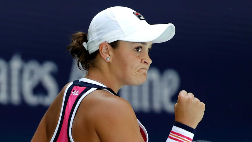 Ash Barty wearing a cap and pink top pumps her fist.