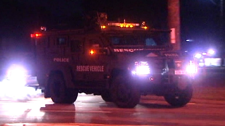 An armoured police car drives along a road.