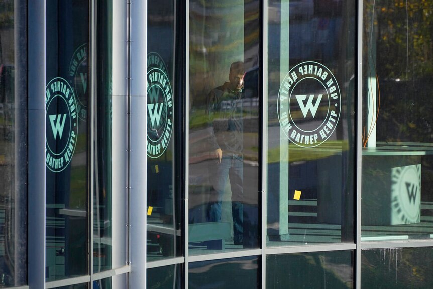 A man is seen inside the "PMC Wagner Centre" through glass doors with the group's logo on them.