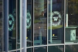 A man is seen inside the "PMC Wagner Centre" through glass doors wit the group's logo on them.