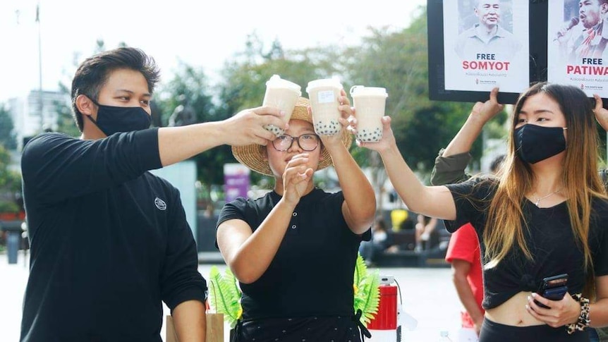 Three protesters hold bubble tea at a protest.