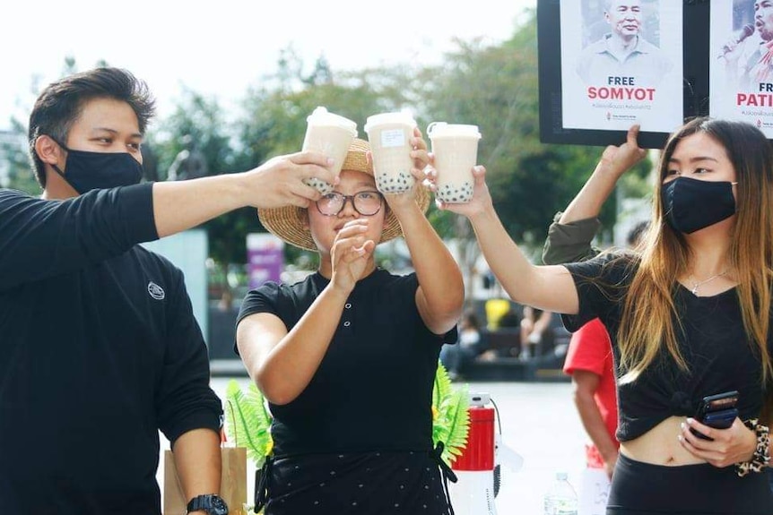 Three protesters hold bubble tea at a protest.