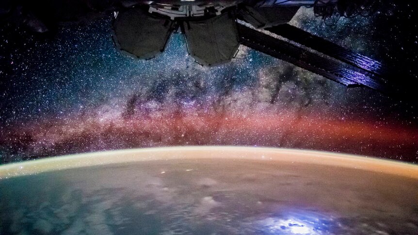 A view of Earth from the International Space Station, with part of the station at the top, and night skies below.