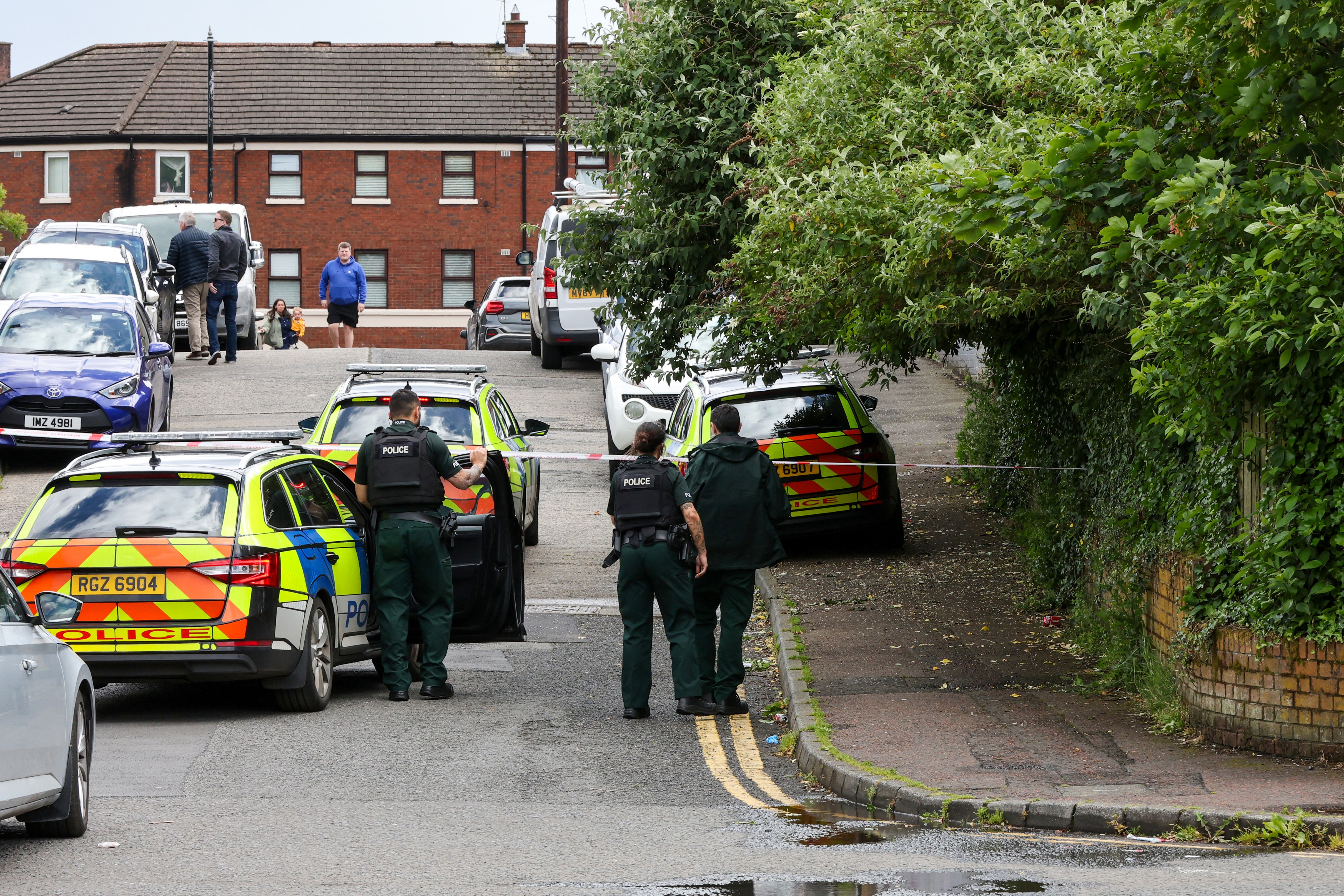 police cars and police line a suburban street in belfast
