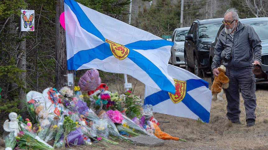 A older man pays his respects placing a teddy bear at a roadside memorial in Portapique.
