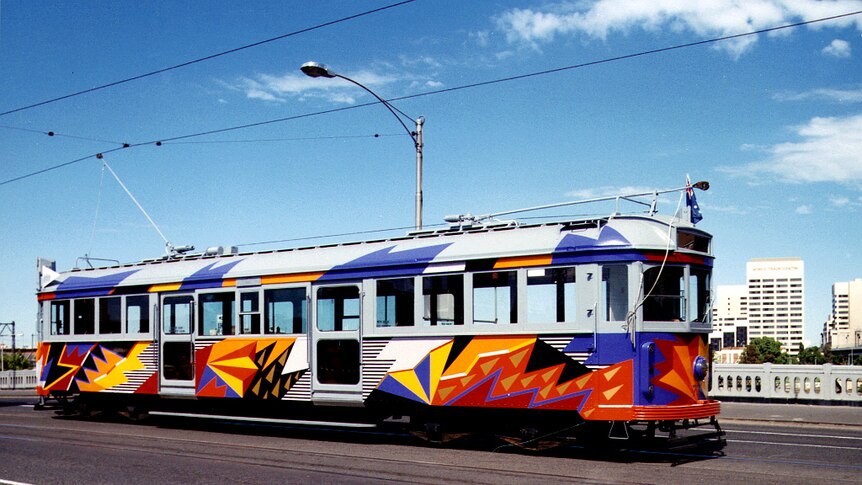 Tram covered in painted artwork on Flinders St bridge.