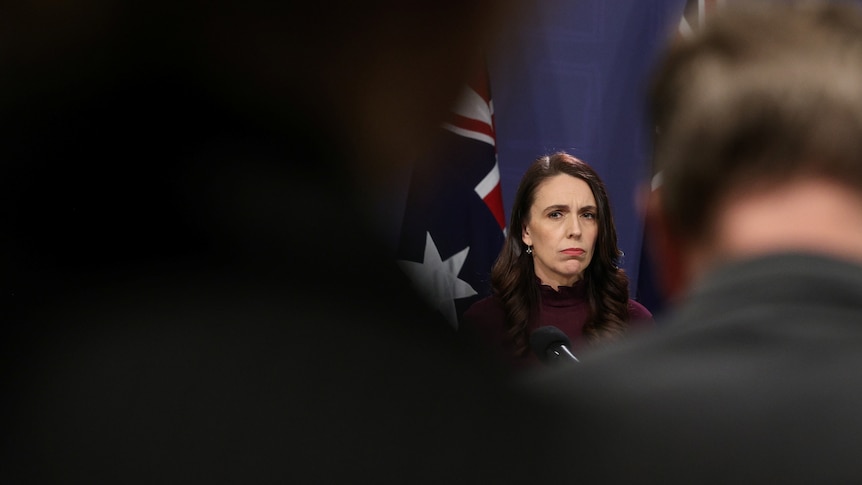 Jacinda Ardern can be seen, but her face is framed by shadows in the foreground. 