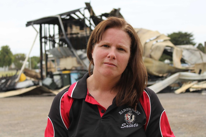 Tamara Ploenges stands in front of the burned wreckage of the clubhouse.