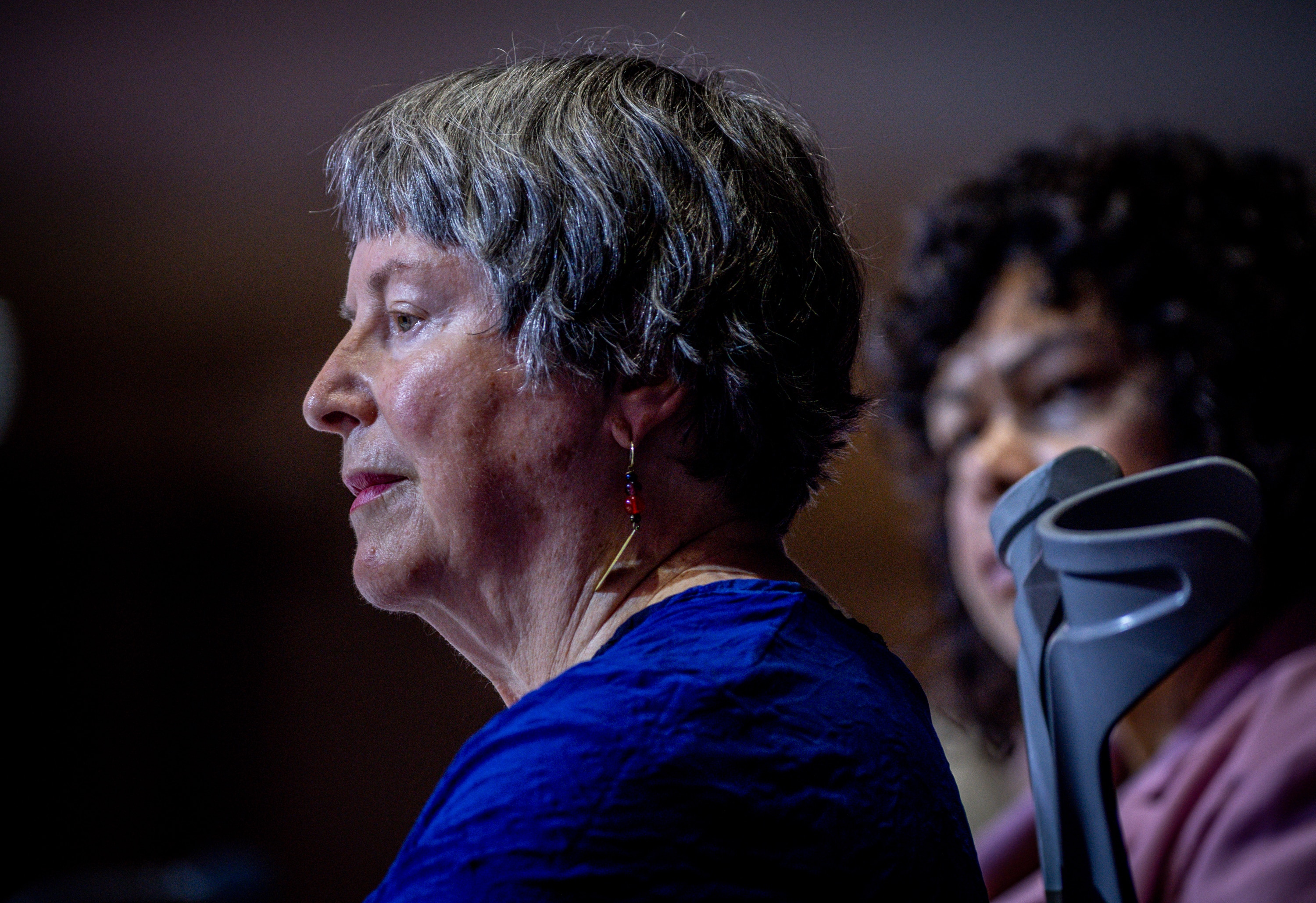 A middle-aged white woman on-stage speaking. She is a wheelchair user