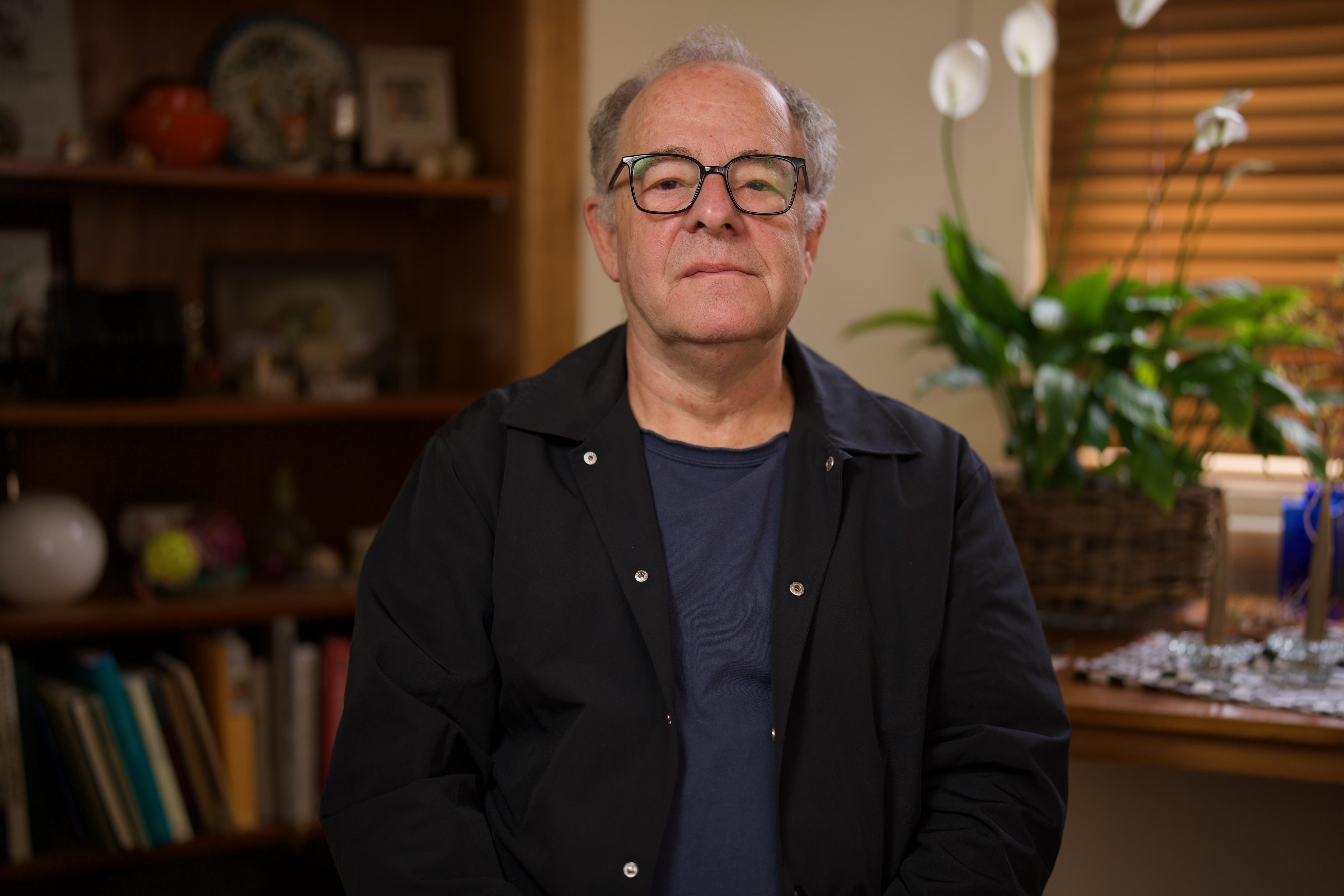 El hombre con top oscuro mira a la cámara