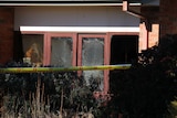 The window of a house which was on fire. There is emergency tape in the foreground.