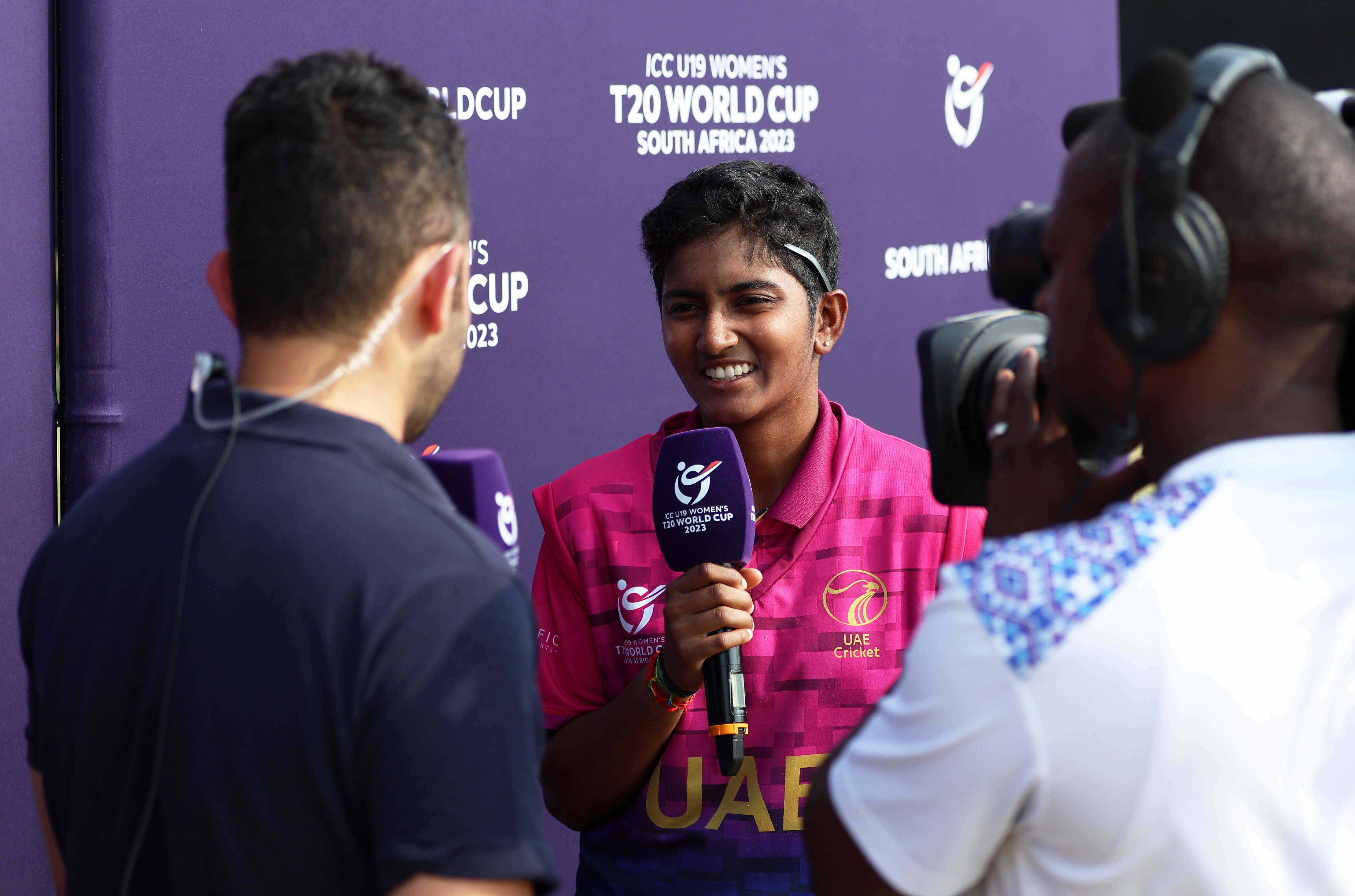 A woman holds a microphone while a man films her with a camera.