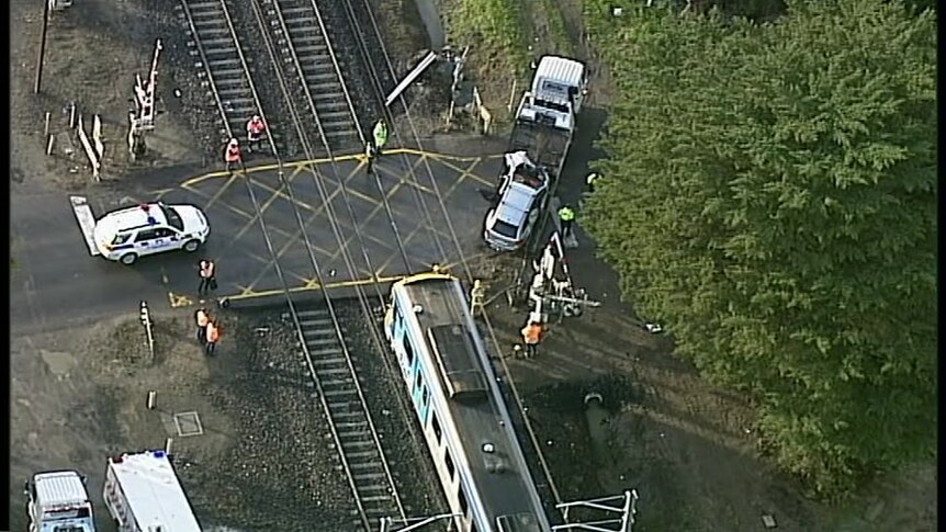 An aerial image of a train being put onto the tray of a truck while emergency workers supervise.