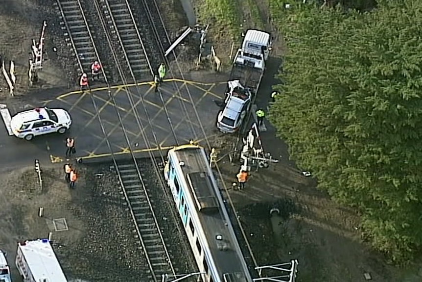 An aerial image of a train being put onto the tray of a truck while emergency workers supervise.