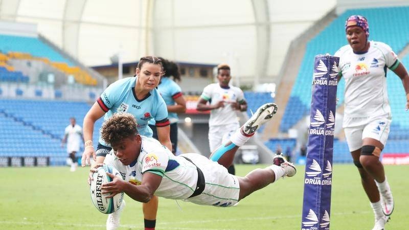 A female rugby player for Fiji scores a try.