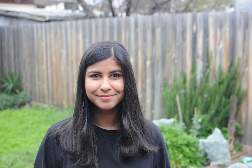 Rushani Epa - a young Sri Lankan Australian woman - standing in a backyard, smiling small for the camera