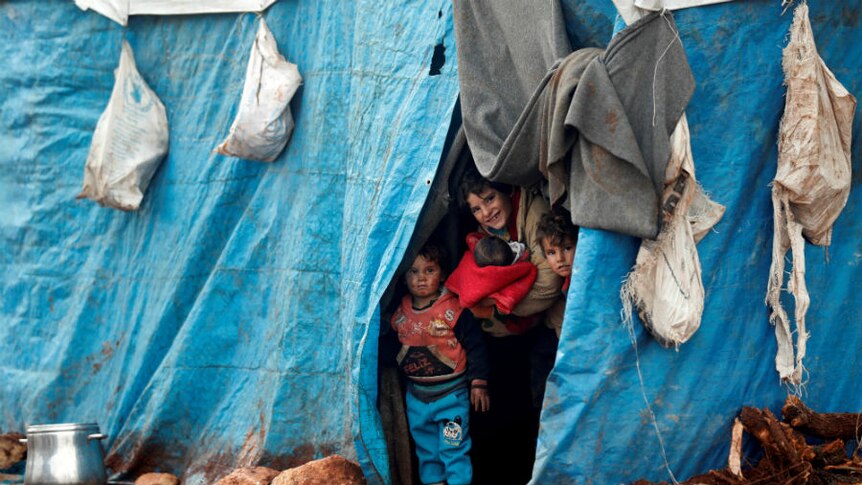 Displaced Syrian children look out from their tents at Kelbit refugee camp,