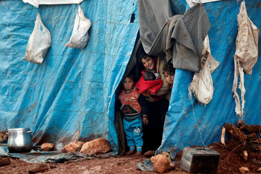 Displaced Syrian children look out from their tents at Kelbit refugee camp,