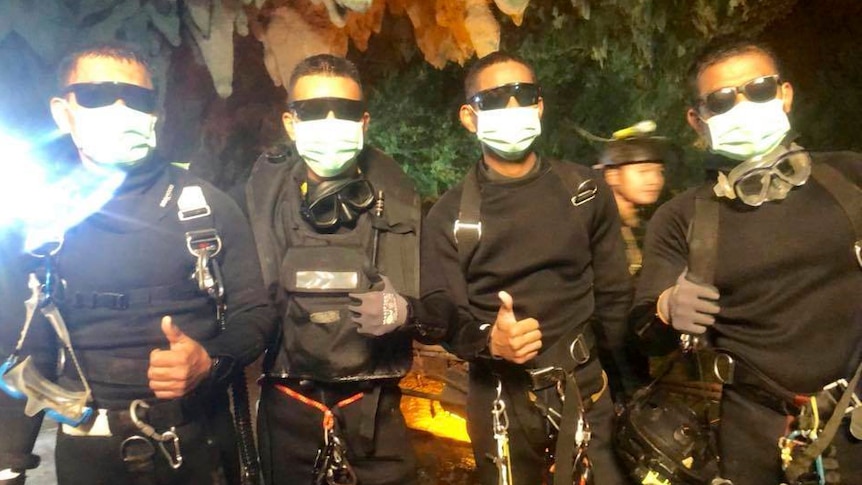 Thai Navy SEALs pose for a photo, making a thumbs up gesture.