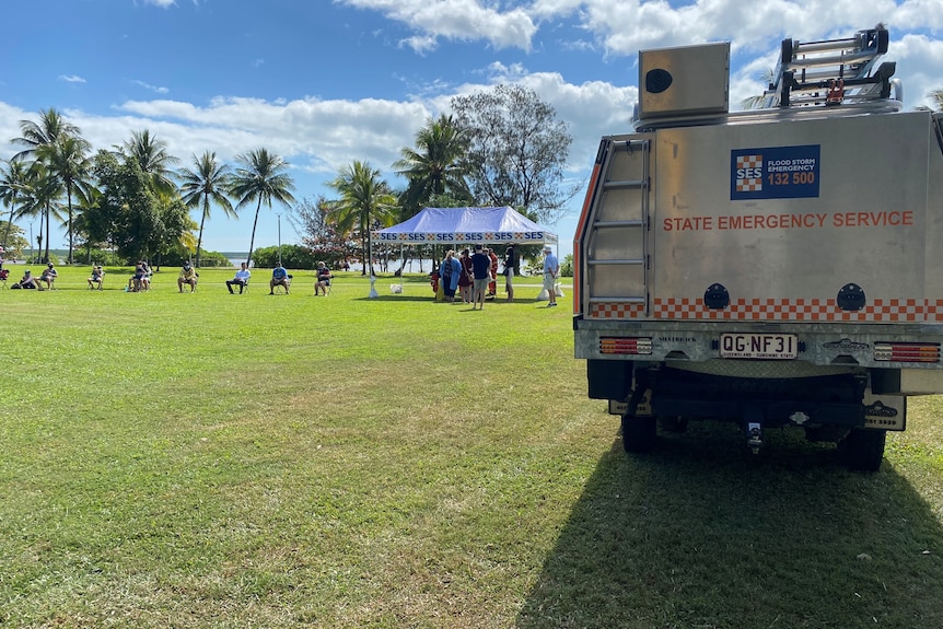 A SES vehicle with a tent in background, people lined up on chairs, socially distanced.