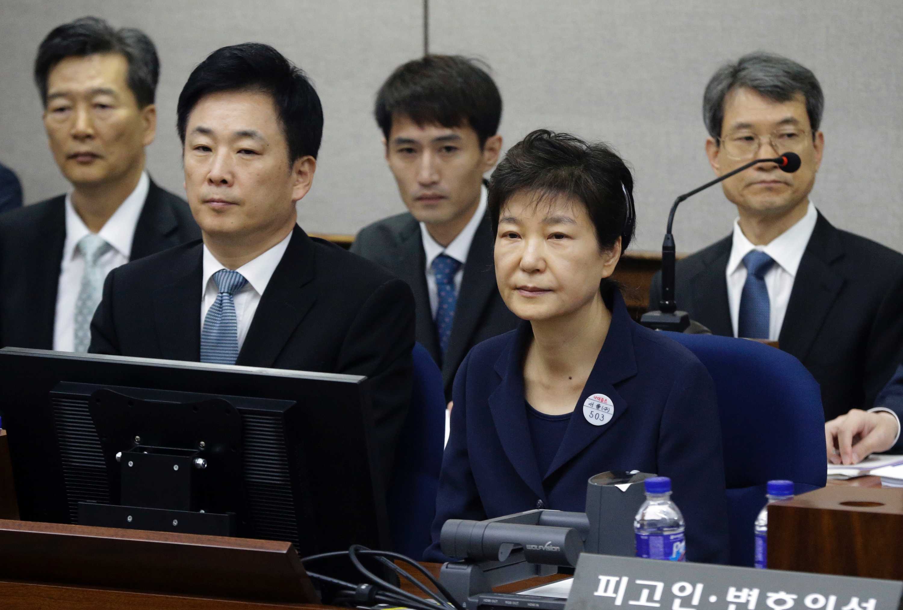 Park Geun-hye sits in court surrounded by her legal team and supporters.