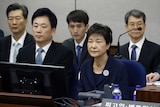 Park Geun-hye sits in court surrounded by her legal team and supporters.