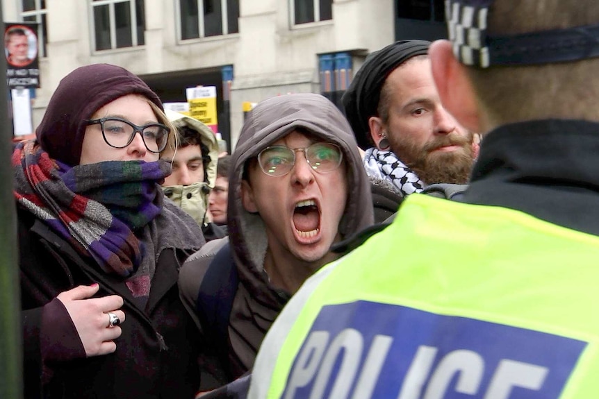 A protester screams at a police officer.