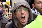 A protester screams at a police officer.