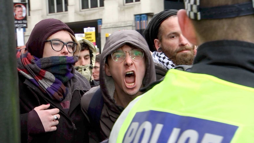 A protester screams at a police officer.
