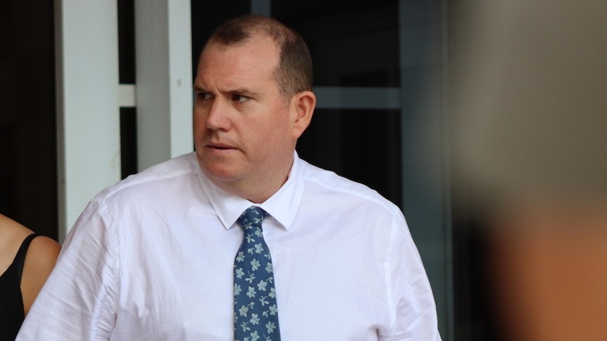 Man with blue tie outside court looking to the side 