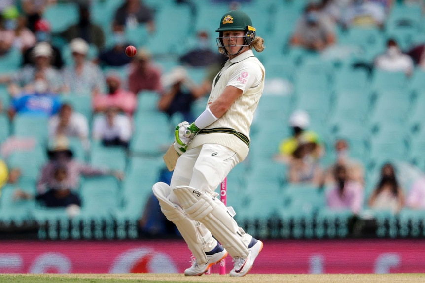 Will Pucovski leans back and watches a ball go past him while wearing cricket whites