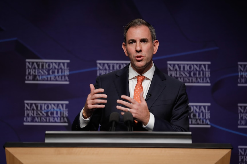 Jim gestures as he speaks at a podium.