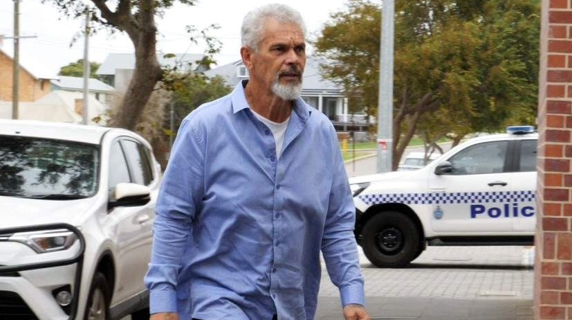 A man in a blue shirt approaches a court building.