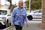A man in a blue shirt approaches a court building.