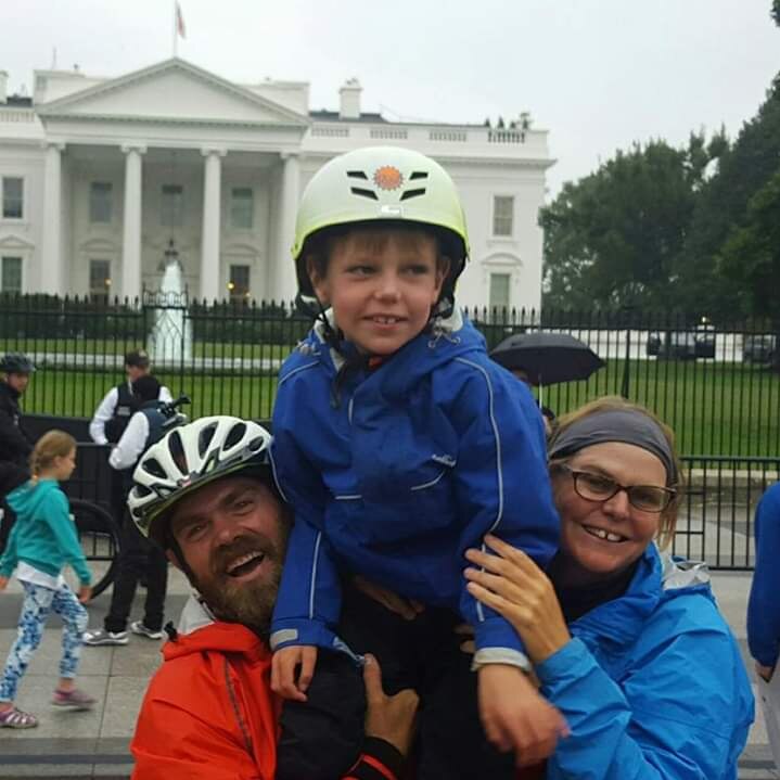 A man and a woman hold a young boy up on their shoulders in front of the White House.  They are all smiling.