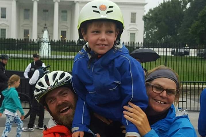 A mother, father and child smiling and posing for a photo in front of the White House.