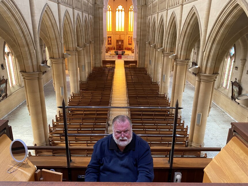 A man sitting at a huge organ in a massive cathedral.