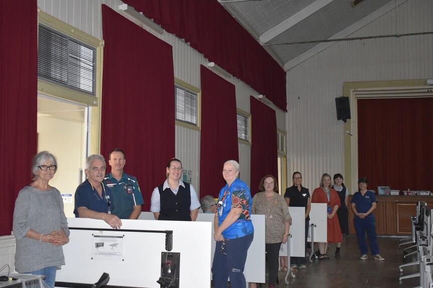 A group of heath care professionals in a hall with locals about to receive their second vaccination shot