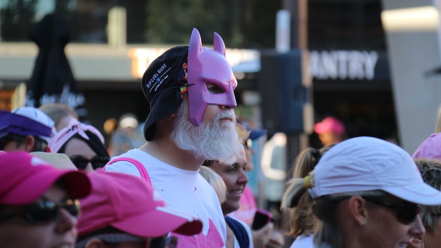 A man dressed in a pink Batman mask