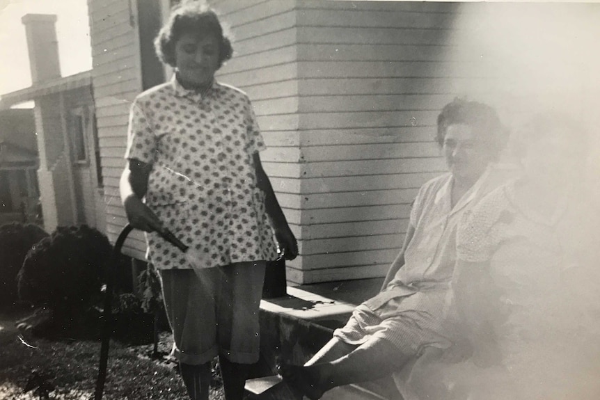 Black and white photo of a pregnant woman watering the garden