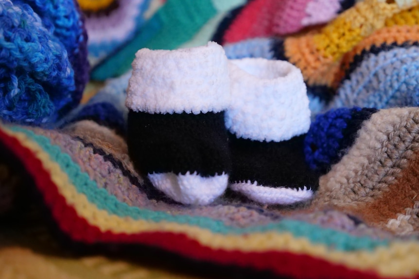 A pair of crocheted baby booties sitting on a rug