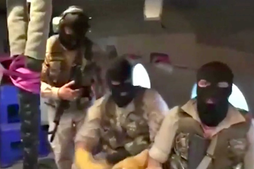 Men in ski masks sit on board a military helicopter
