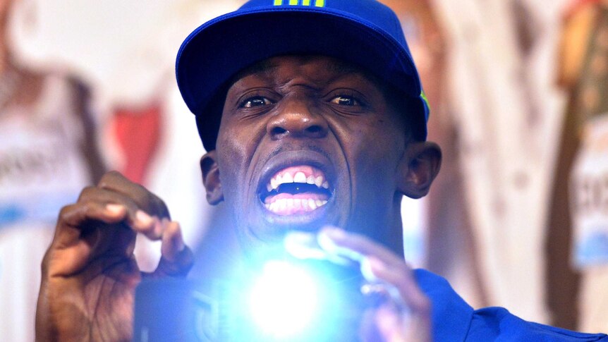 Usain Bolt takes a photo during a press conference.