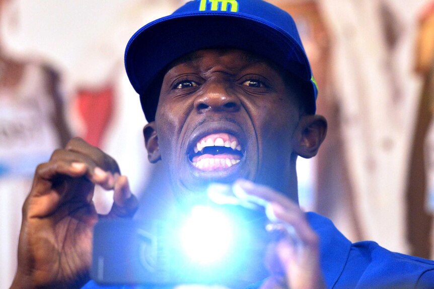 Usain Bolt takes a photo during a press conference.