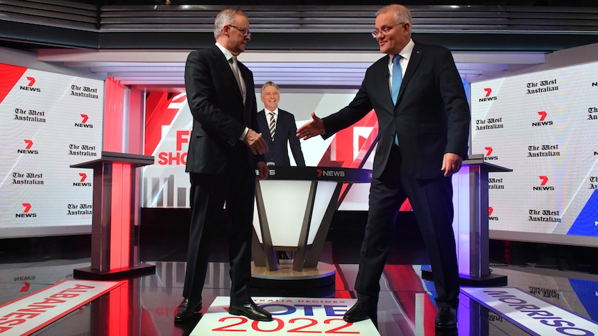 Anthony Albanese and Scott Morrison hesitate ahead of shaking hands.