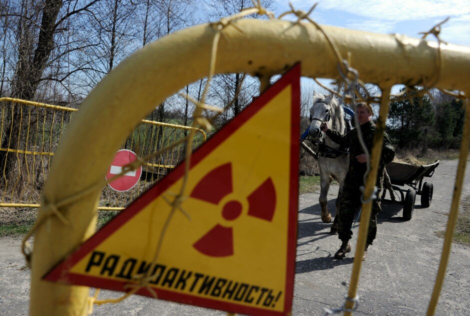 A radiation warning sign is seen as a man leads a horse near the village of Novoselki.