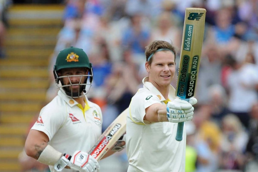 Steve Smith raises his bat while batting partner Matthew Wade looks on from behind. England fielder Jason Roy looks unimpressed.